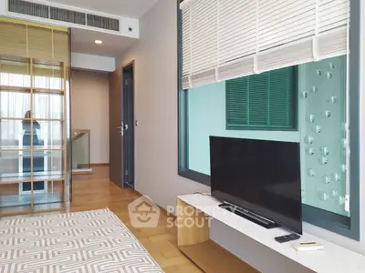 Modern bedroom with TV and large window, featuring stylish decor and wooden flooring.