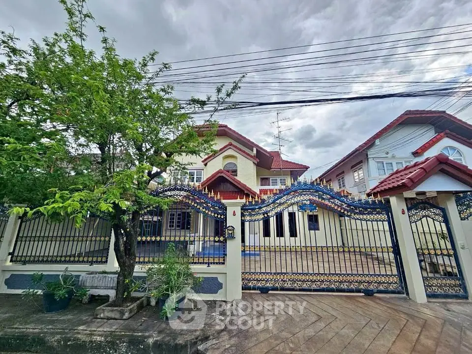 Charming two-story house with ornate fence and lush greenery in a serene neighborhood.