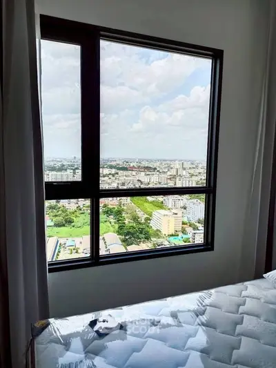 Stunning city view from a high-rise apartment bedroom window, showcasing urban landscape and skyline.