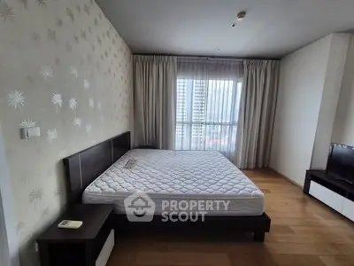 Spacious bedroom with large window and modern decor in a high-rise apartment.