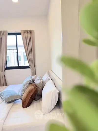 Cozy bedroom with stylish pillows and large window offering natural light
