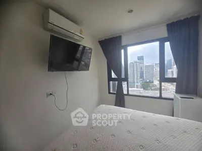 Modern bedroom with city view, featuring wall-mounted TV and air conditioning.