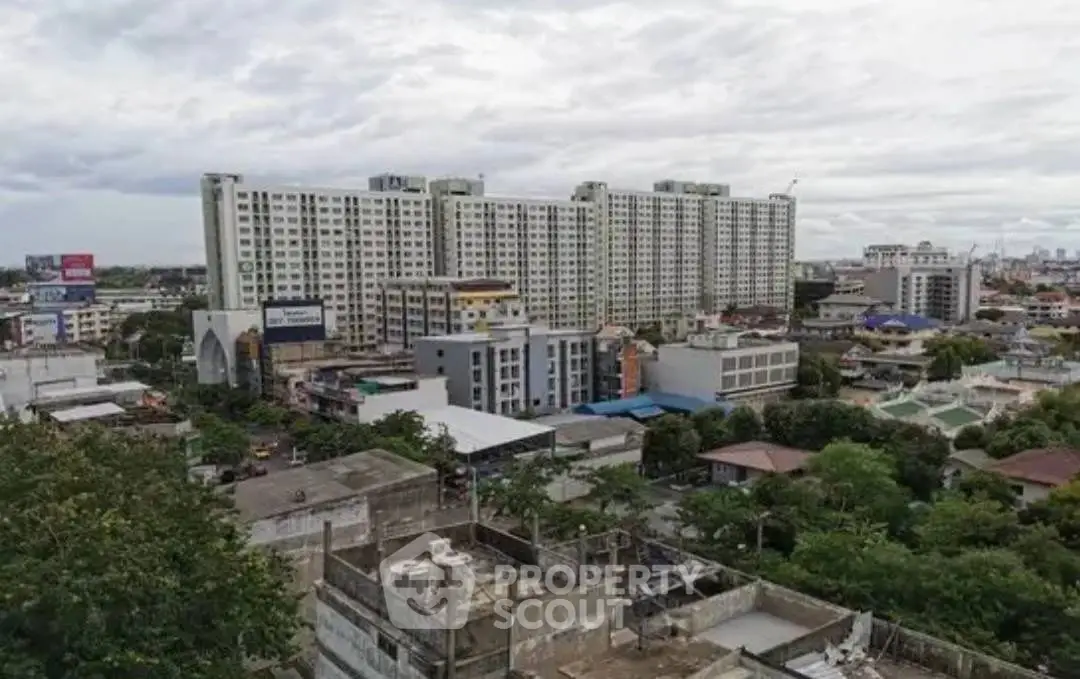 Panoramic view of urban residential buildings with lush greenery and cloudy sky.