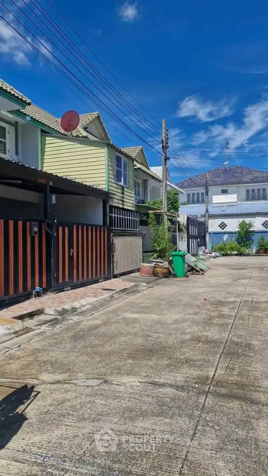 Charming residential street with colorful houses and clear blue sky.
