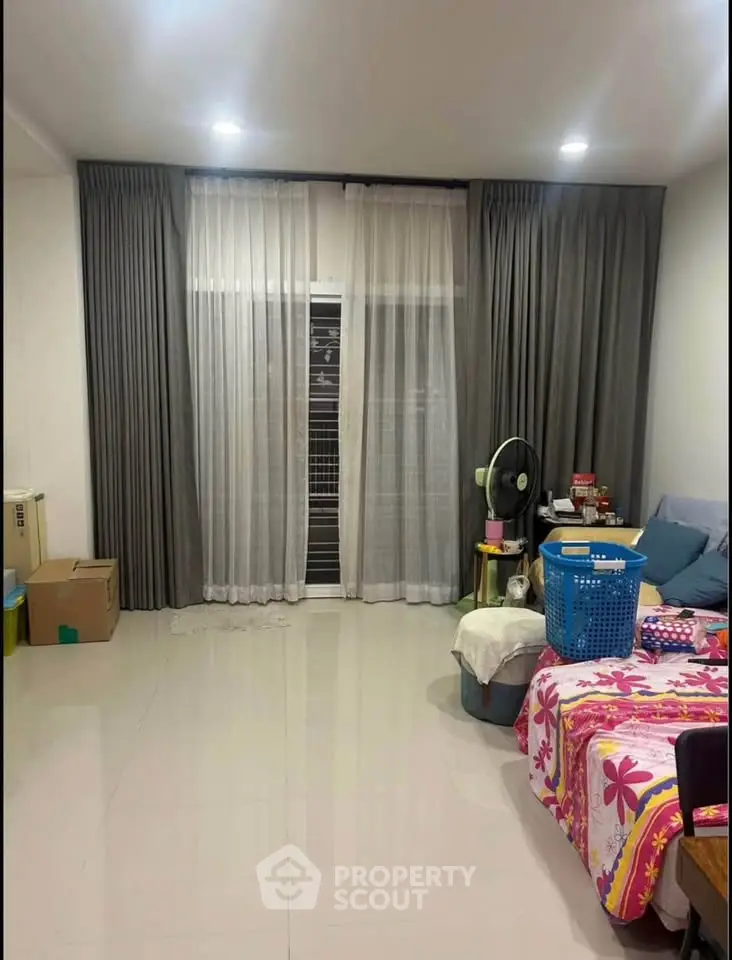 Spacious living room with large windows and modern curtains, perfect for cozy family gatherings.