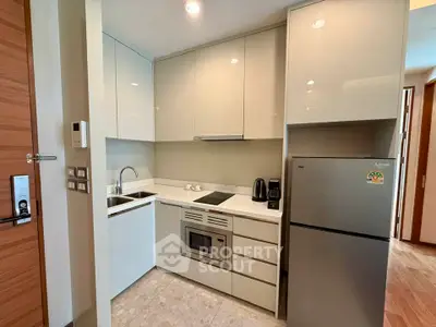 Modern compact kitchen with sleek cabinetry and built-in appliances in a stylish apartment.