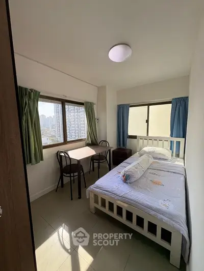 Cozy bedroom with city view, featuring a double bed and dining table.