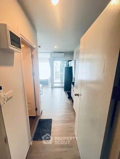 Modern apartment entrance with open view to living area and balcony, featuring sleek flooring and bright lighting.