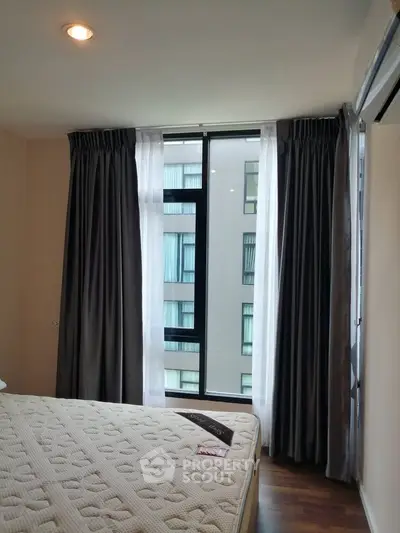 Cozy bedroom with large window and elegant curtains in modern apartment