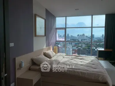 Luxurious bedroom with stunning city view from large windows, featuring elegant decor and cozy bedding.