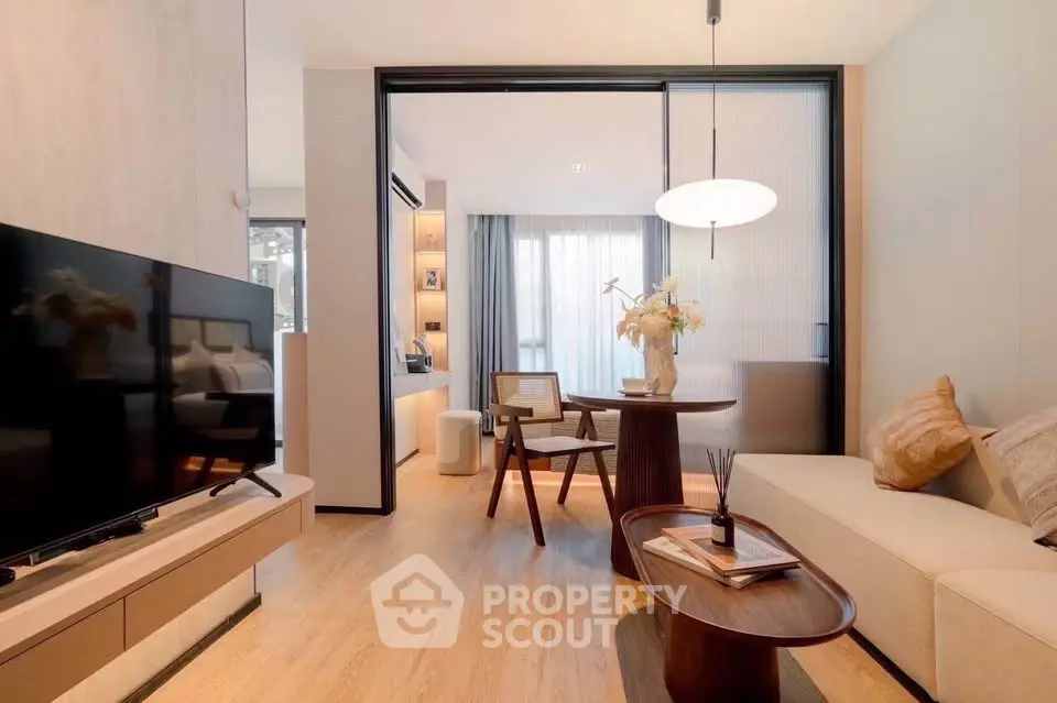 Modern living room with stylish decor and natural light, featuring a cozy seating area and sleek TV setup.