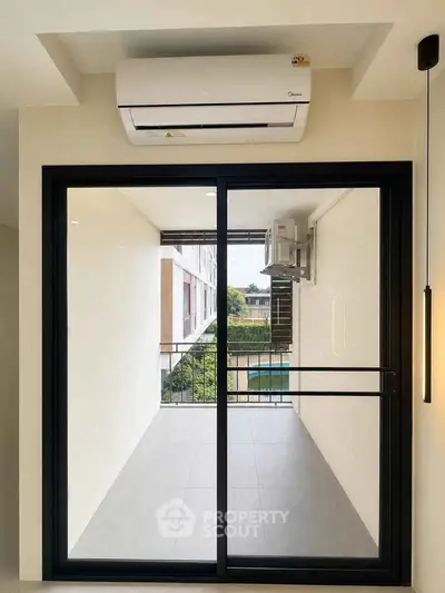 Modern apartment balcony with sliding glass doors and air conditioning unit.