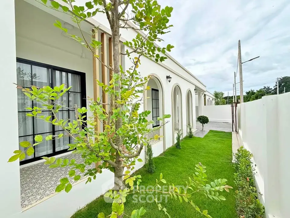 Charming exterior view of a modern home with lush green garden and elegant arched windows.