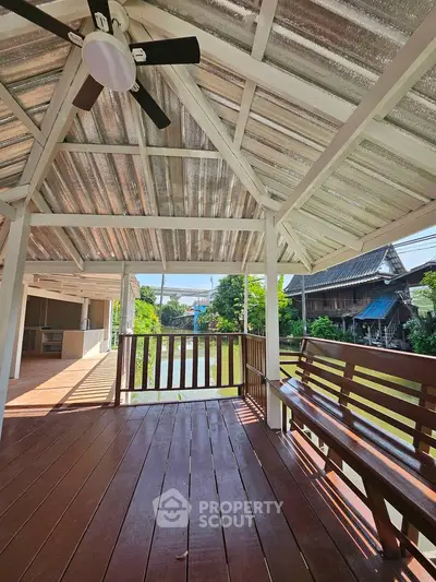 Charming wooden balcony with scenic view of lush greenery and traditional houses.