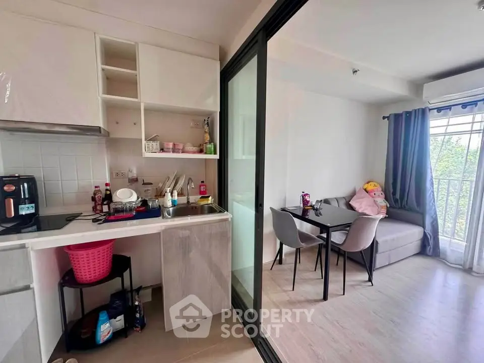 Modern apartment with compact kitchen and cozy dining area, featuring a small balcony with natural light.