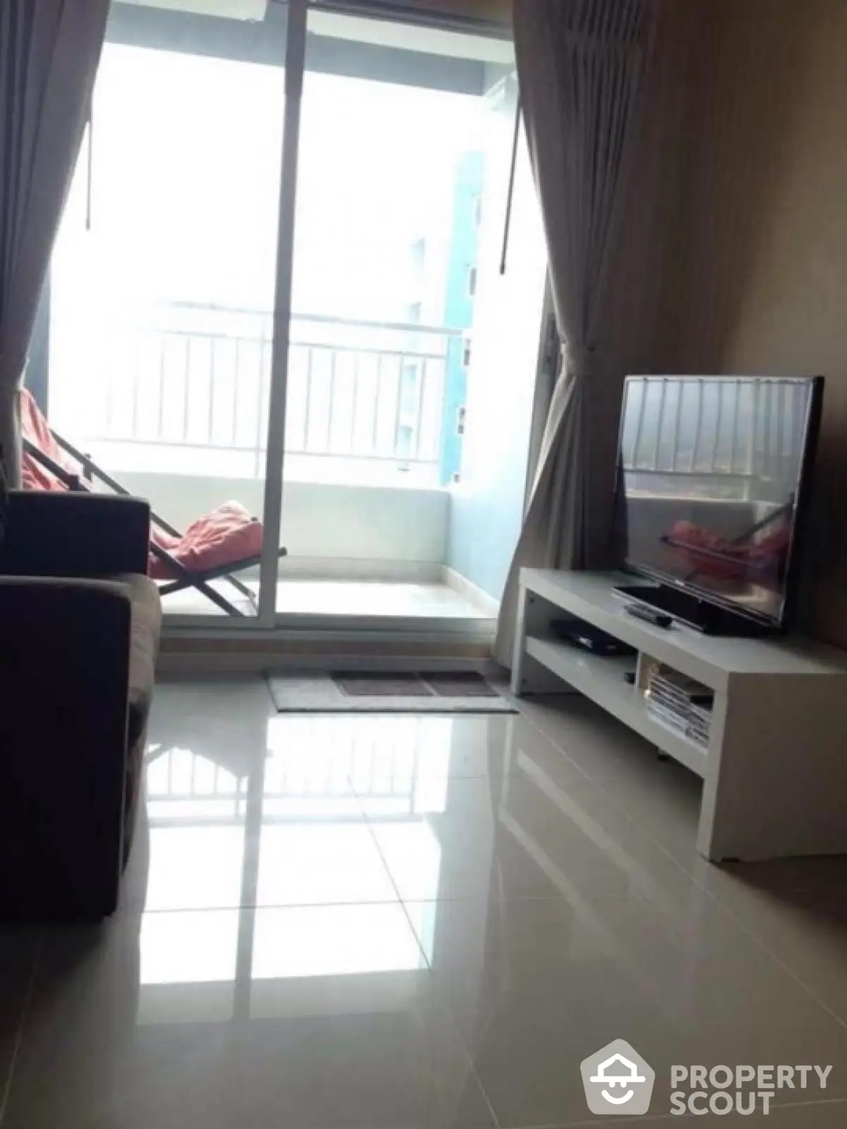 Modern living room with sleek TV setup and balcony view, perfect for urban living.