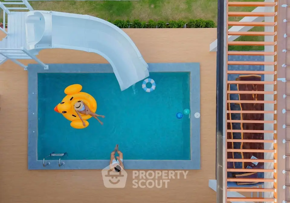 Stunning aerial view of modern pool with slide and inflatable duck, perfect for luxury relaxation.