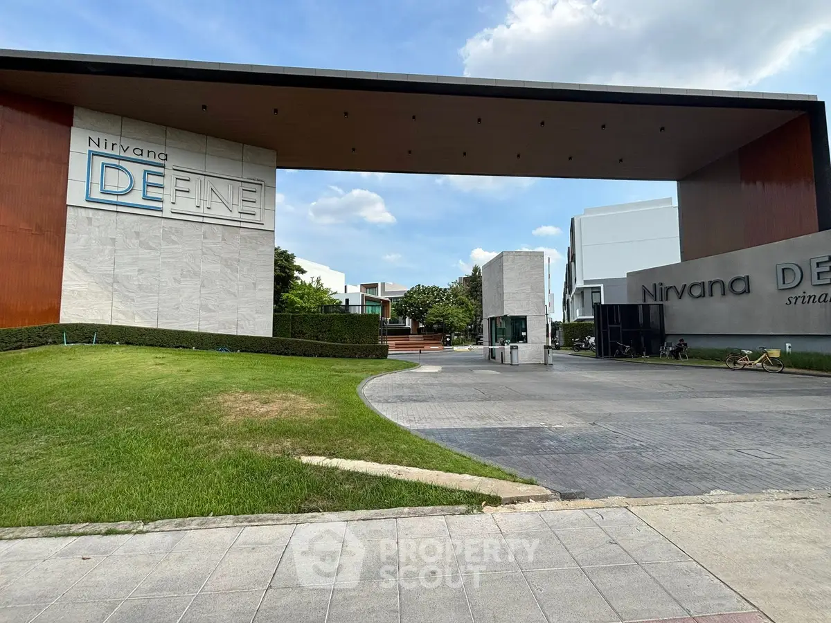 Modern gated community entrance with sleek architecture and lush landscaping.