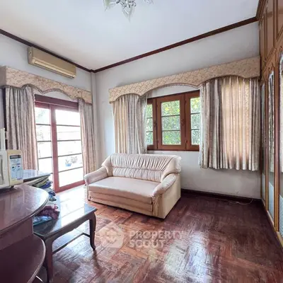 Charming living room with parquet flooring and cozy sofa, featuring large windows for natural light.