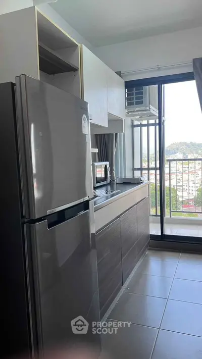 Modern kitchen with sleek appliances and balcony view in urban apartment