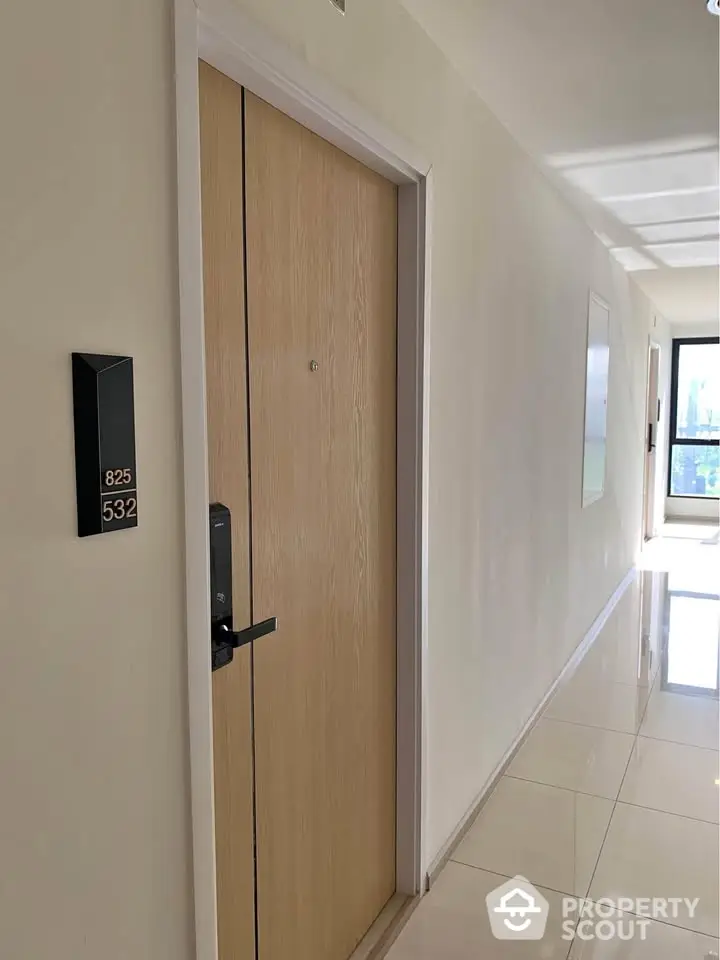 Modern apartment hallway with sleek wooden door and glossy tiled floor