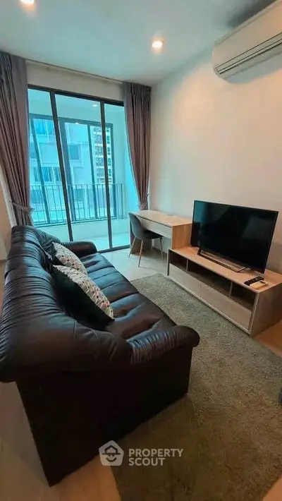Modern living room with leather sofa, TV, and balcony view in a stylish apartment.