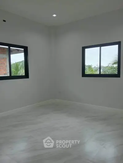 Spacious empty room with large windows and tiled flooring, offering a bright and airy atmosphere.