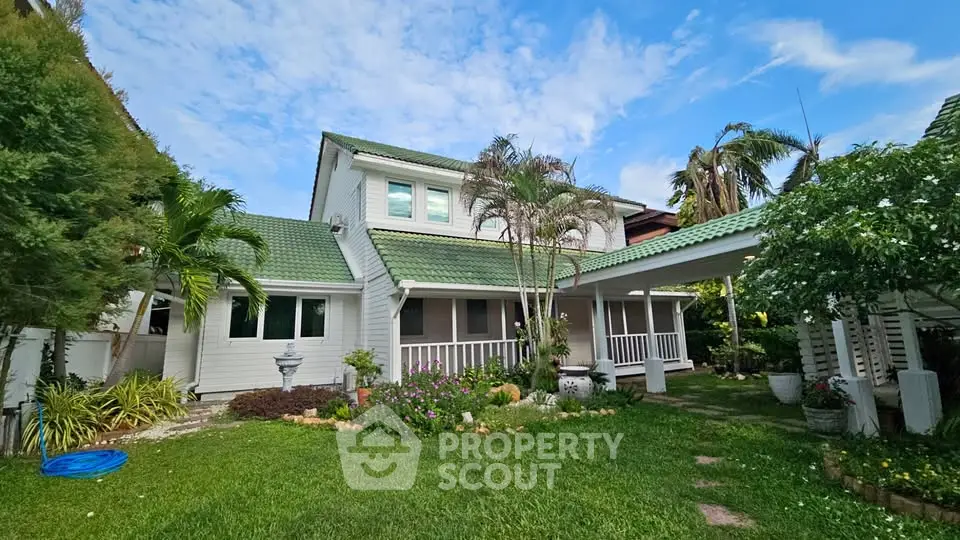 Charming two-story house with lush garden and green roof, perfect for serene living.