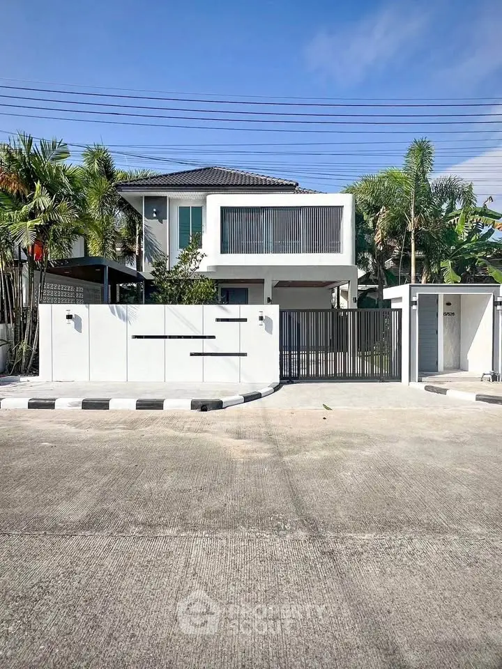 Modern two-story house with sleek design and lush greenery, featuring a secure gated entrance.