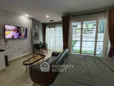 Modern bedroom with large windows and stylish decor, featuring a wall-mounted TV and cozy seating area.