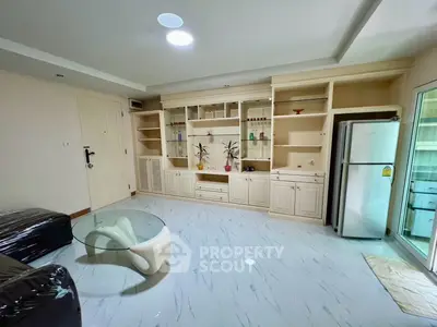 Spacious living room with modern glass table and built-in shelving, perfect for stylish urban living.
