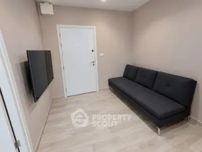 Modern minimalist living room with sleek black sofa and wall-mounted TV