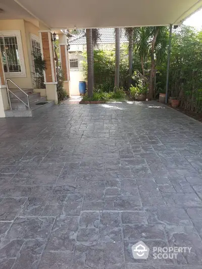 Spacious driveway with textured paving in a serene residential setting.