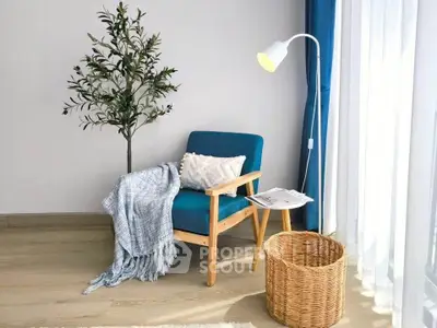 Cozy living room corner with blue armchair, floor lamp, and decorative plant.