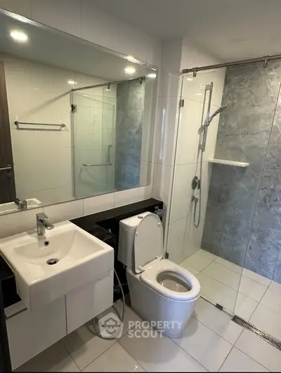 Modern bathroom with sleek design, featuring a glass shower enclosure and contemporary fixtures.