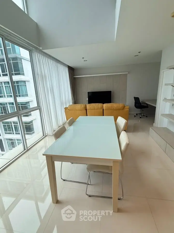 Spacious modern living room with large windows and stylish furniture in a high-rise apartment.