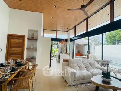 Luxurious open-plan living room with modern decor and pool view, featuring high ceilings and elegant furnishings.