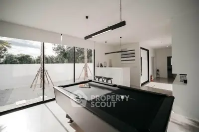 Modern living room with pool table and large windows overlooking garden