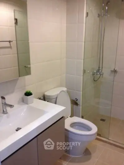 Modern bathroom with glass shower and sleek vanity in a contemporary home.