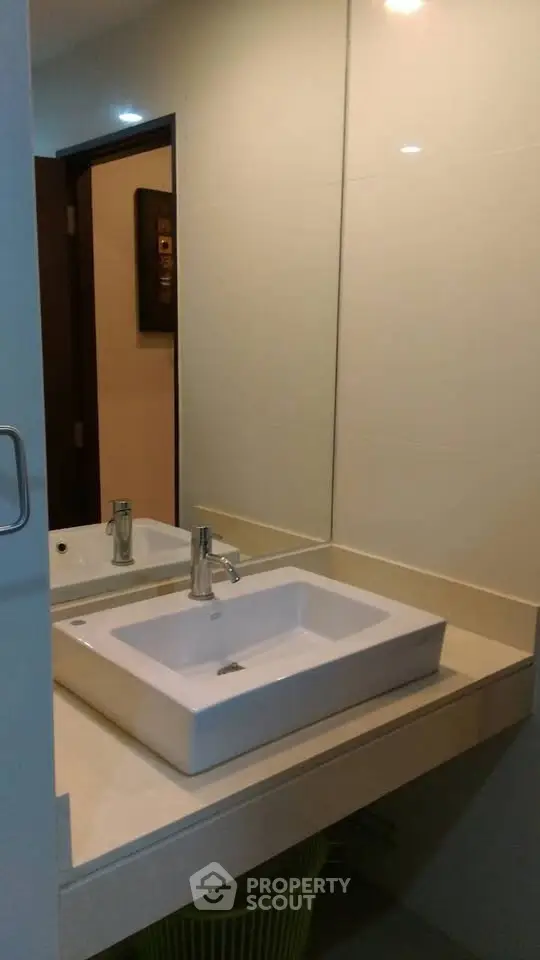 Modern bathroom with sleek sink and large mirror in contemporary apartment.