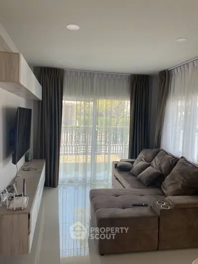 Modern living room with cozy sofa and large windows offering natural light.