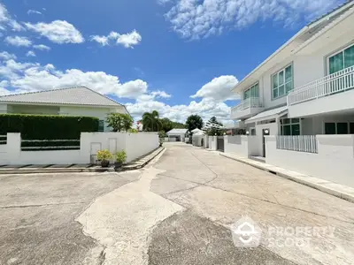 Charming residential street with modern white houses and clear blue sky