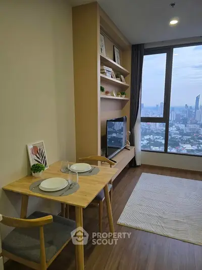 Modern living room with dining area and city view, featuring stylish shelving and cozy decor.