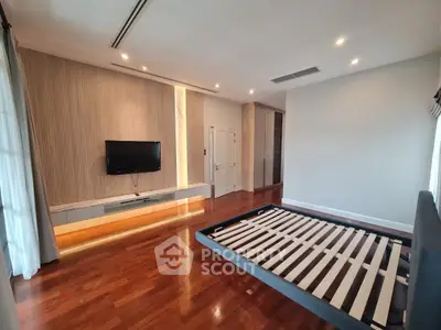 Spacious bedroom with wooden flooring and modern TV setup