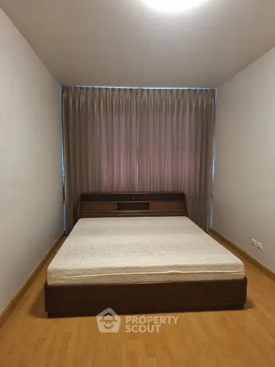 Spacious bedroom with wooden flooring and large bed, perfect for relaxation.