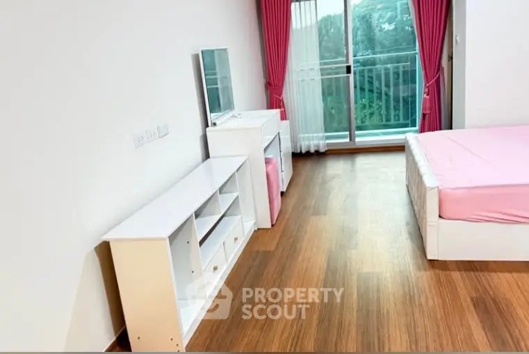 Spacious bedroom with balcony and pink accents in modern apartment