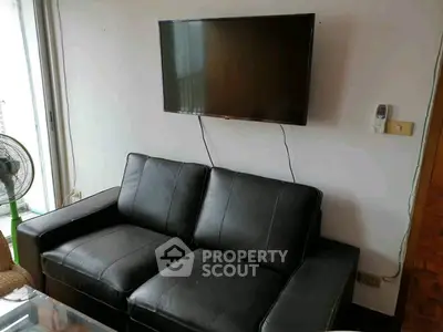 Modern living room with black leather sofa and wall-mounted TV