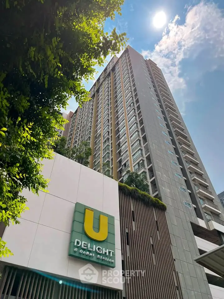 Modern high-rise condominium with lush greenery and clear blue sky.