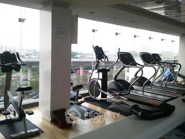 Modern gym with city view featuring treadmills and exercise bikes
