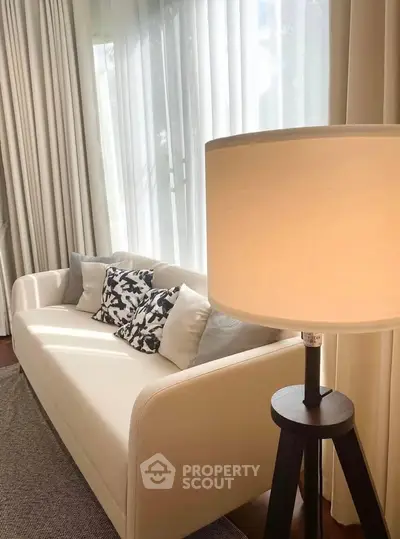 Elegant living room with cozy white sofa and stylish floor lamp by large window.